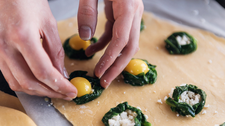 hands placing egg yolk in ravioli