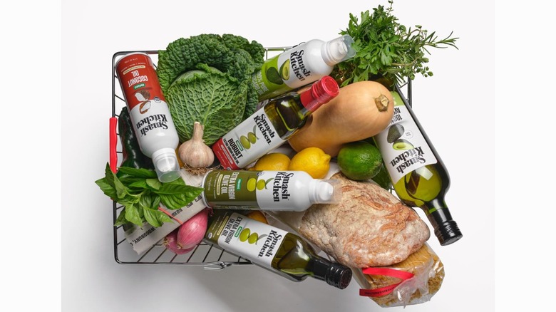 A grocery basket containing fresh vegetables, bread, and Smash Kitchen oils