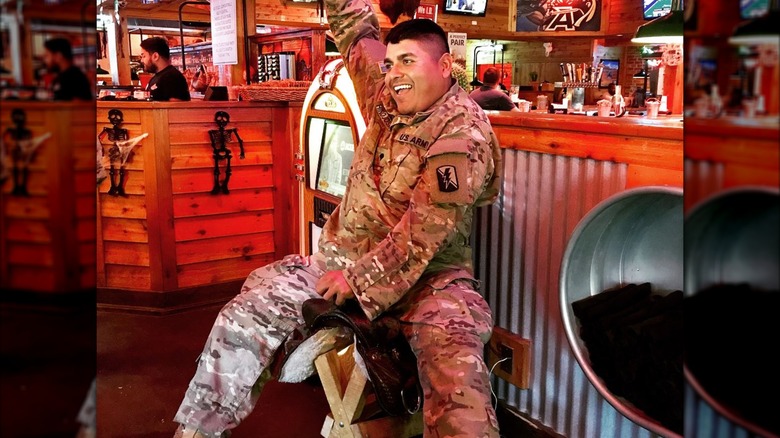 Military man celebrating on the "birthday saddle"