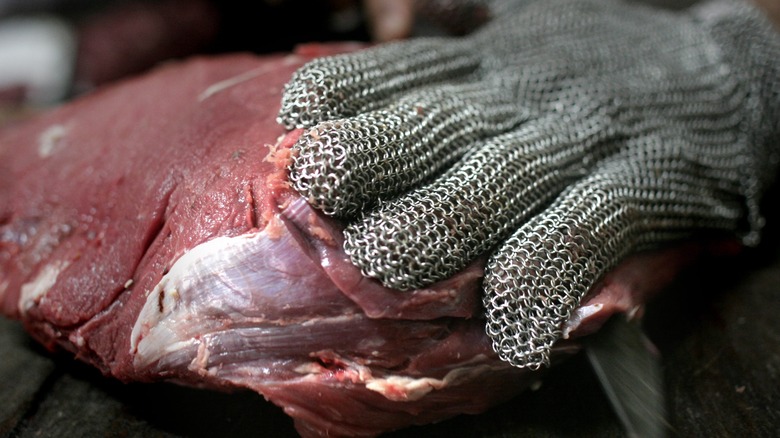 Kosher butcher's hand inspects fresh meat