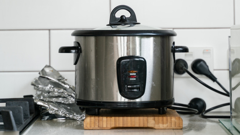 A large rice cooker plugged into the wall on a kitchen counter