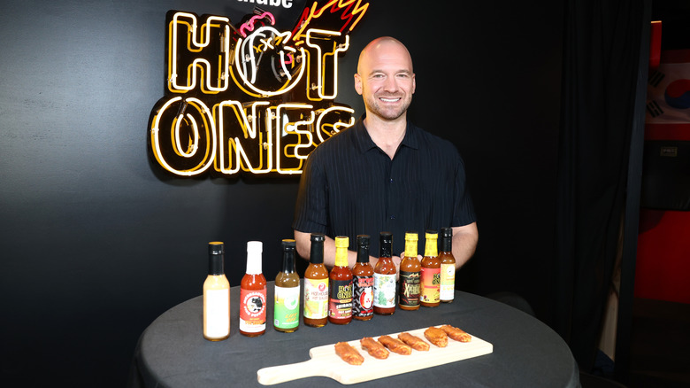 Sean Evans standing behind a table with wings and hot sauces bottles lined up
