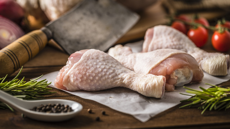 Raw chicken drumsticks on board