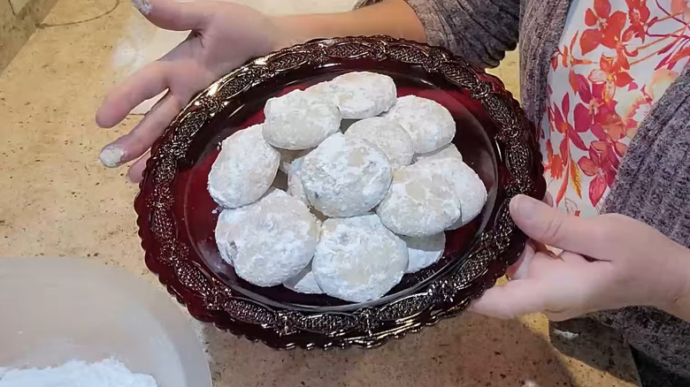 Woman holding red plate of homemade Danish Wedding Cookies