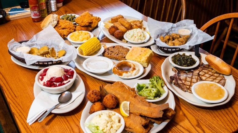 a spread of Po Folks dishes including fried fish, pork chops, ice cream with strawberries, meatloaf, cornbread, mashed potatoes, turnip greens, coleslaw, fried pickles, and fried chicken
