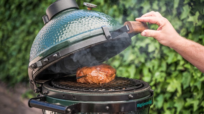 Person opening a Big Green Egg grill