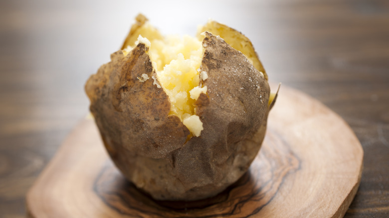 Baked potato on wooden cutting board