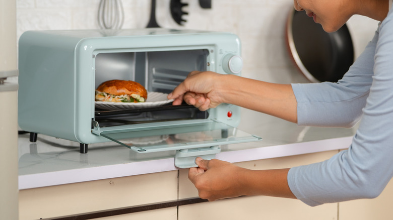 woman cooking food in a blue toaster oven