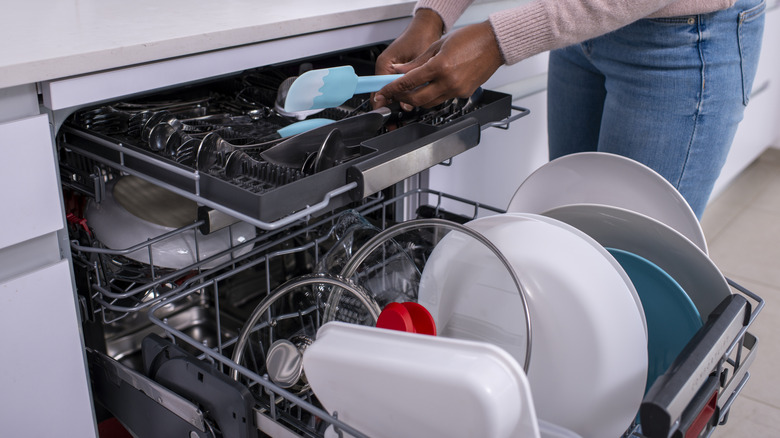 A person putting baking tools into a dishwasher