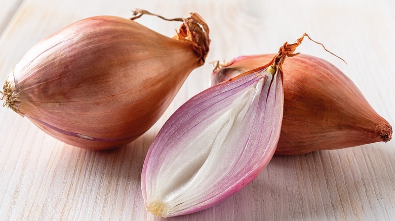 Three shallots on wooden table