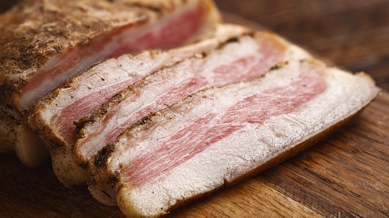 Sliced guanciale on wooden board
