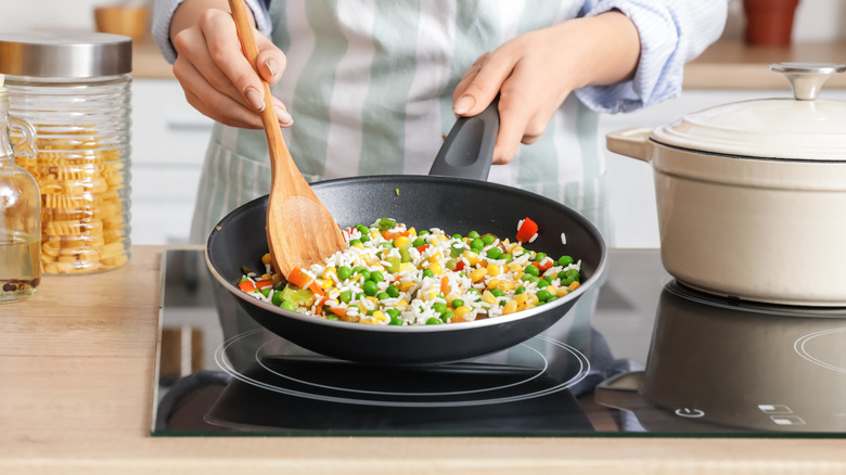 Woman frying rice in pan