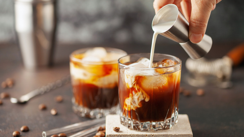 Cream poured as the final ingredient into a white Russian cocktail