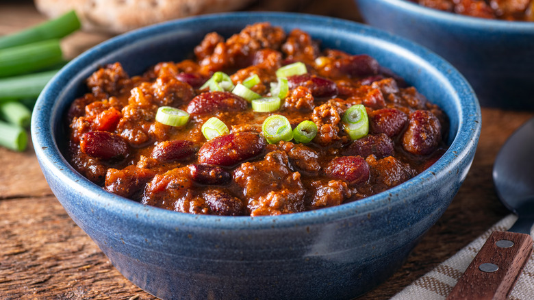 Bowl of chili garnished with scallions 