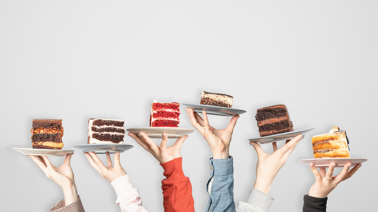 Hands holding plates of cake slices