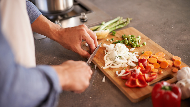 Person chopping vegetables on wooden cutting board