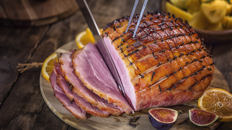 Knife cutting glazed holiday ham