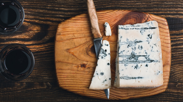 Overhead of cheese on wooden cutting board with knife
