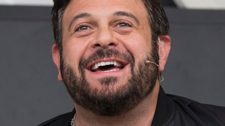 Adam Richman smiling and looking up while wearing microphone