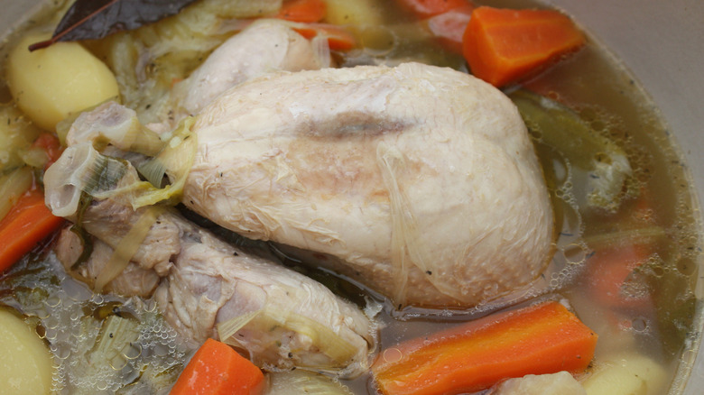 Chicken boiling in a pot with vegetables