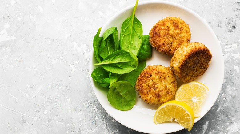 fishcakes lemon and spinach on a plate