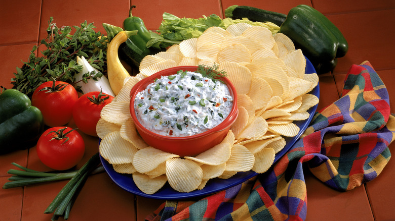 Creamy dip surrounded by potato chips on a plate