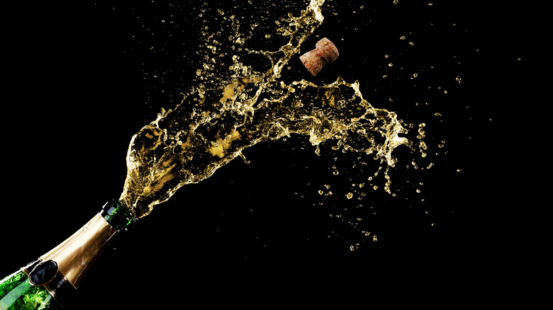 Popped wine bottle spraying champagne