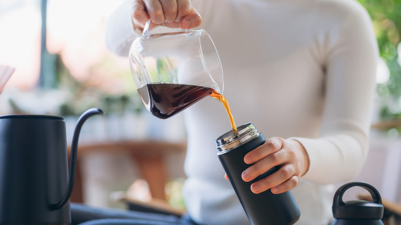 Pouring coffee into travel mug.