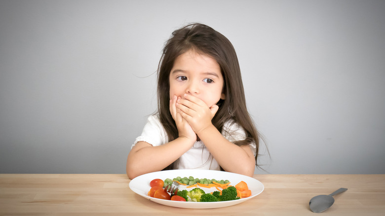 little girl hand mouth plate vegetables