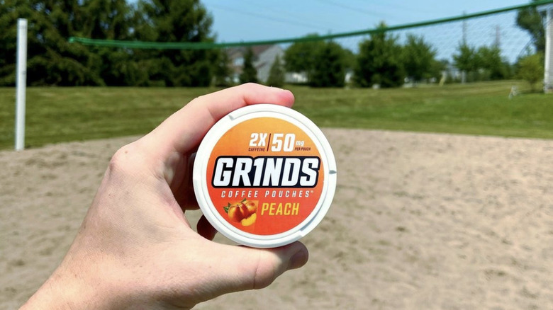Person holding Grinds container