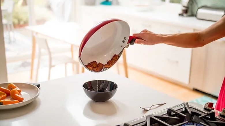 Person using Handy Pan, a cooking pan with a built-in strainer