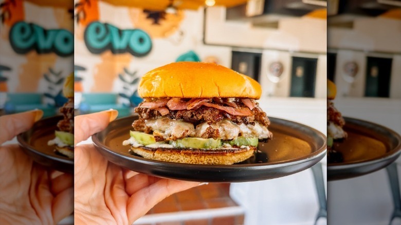 Hand holding Evo sandwich with Evo sign in background