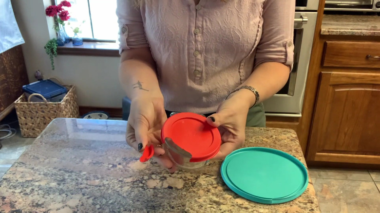 Woman holding a Pyrex bowl with a broken plastic lid