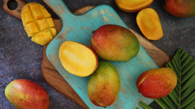 Whole and cut mango on a board