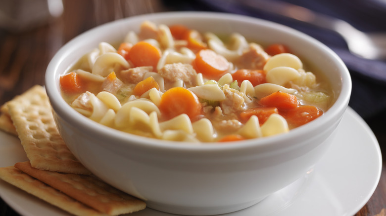 Bowl of chicken noodle soup with crackers