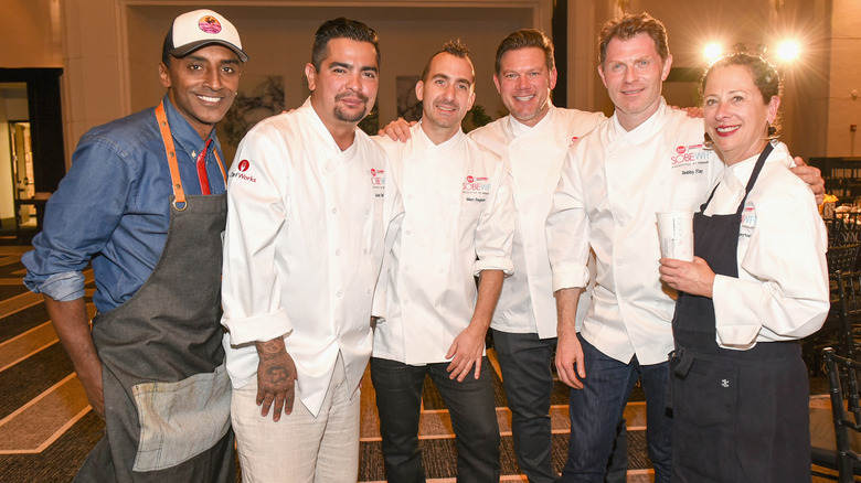 Food Network hosts in white uniforms and aprons taking group photo