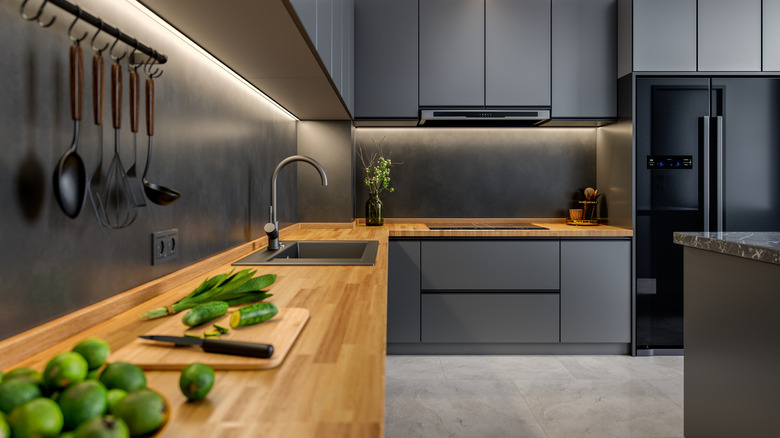 Kitchen with a modern design, featuring gray cabinetry, stainless steel appliances, and a wooden countertop.