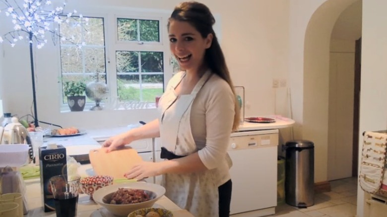 The Pasta Queen smiling in kitchen apron chopping board