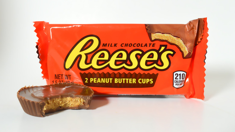 A Reese's cup in front of Reese's candy wrapper