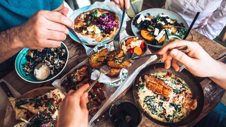 Friends splitting colorful vegetable dishes
