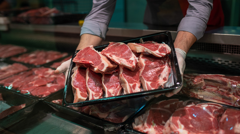 Person holding a tray of meat