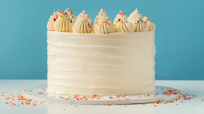 White cake with rainbow sprinkles on blue background