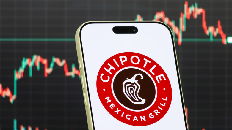 iPhone showing Chipotle logo in front of a digital stock line.