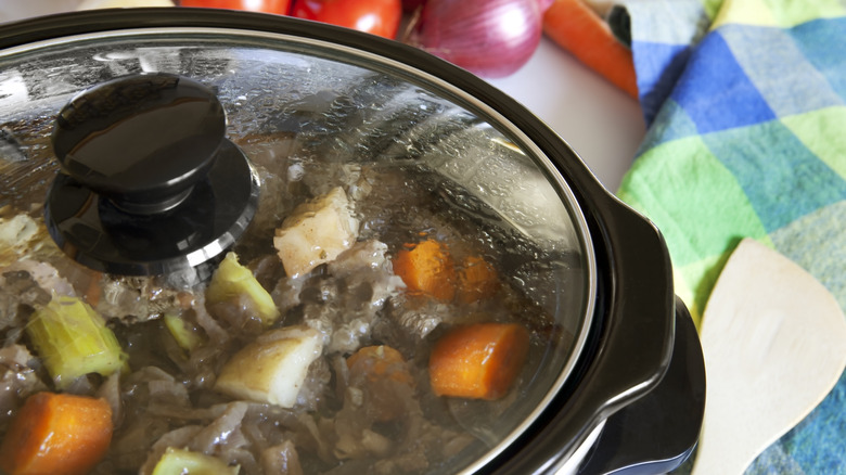 Close up of crock-pot lid with meat, carrots, potatoes and celery visible inside