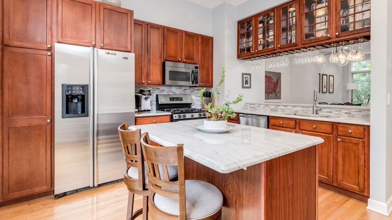 Display kitchen with brown cabinets and stainless steel GE appliances