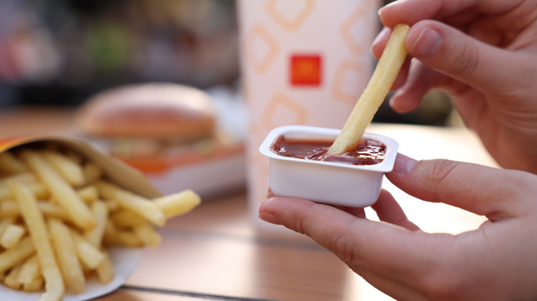 Someone dipping a McDonald's french fry in sauce container