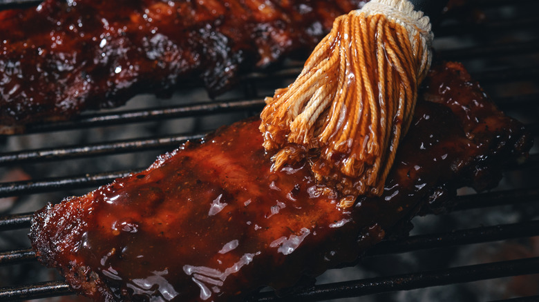 Brushing ribs with barbecue sauce