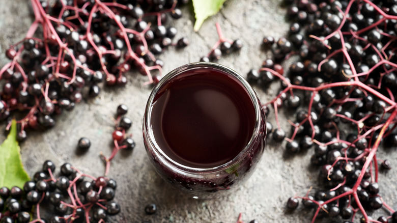 A glass of homemade black elderberry syrup on a table.