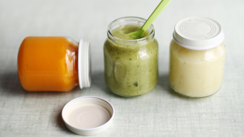 three unlabeled jars of various baby food flavors with a spoon
