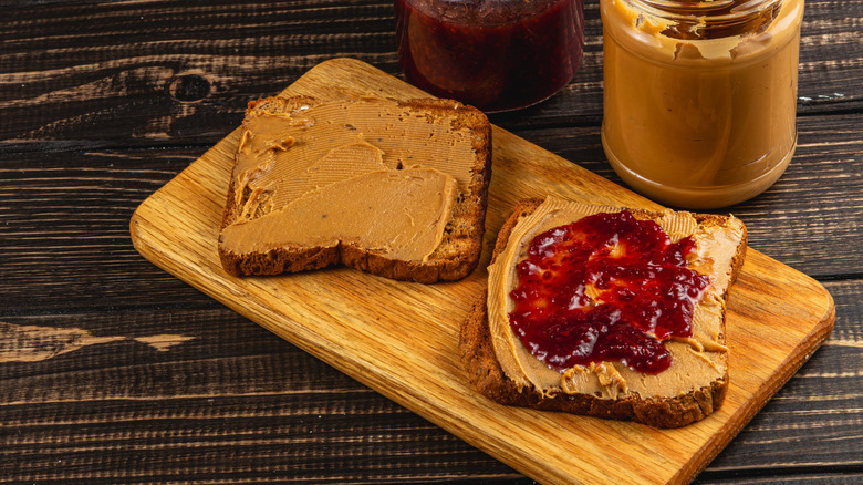 An open-faced peanut butter and jelly sandwich on a cutting board